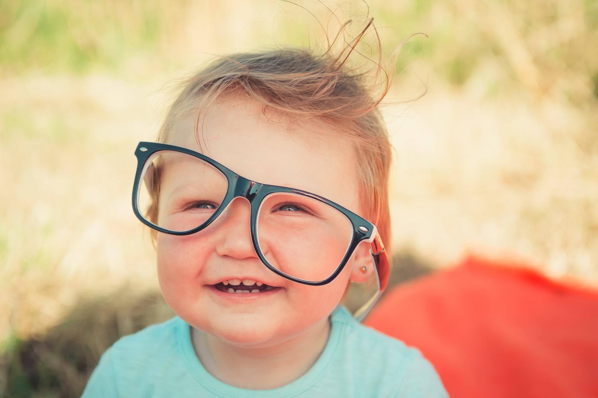 A little girl wearing glasses is making a funny face.