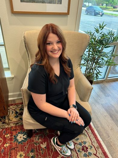 A woman is sitting in a chair in a room and smiling.