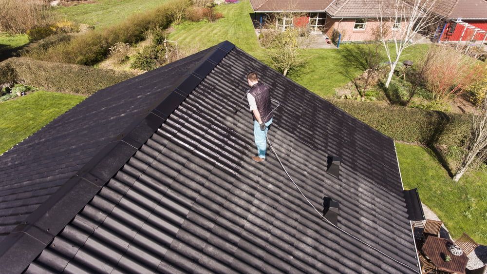 A man is standing on the roof of a house. — AD House Wash & Gutter Cover in East Toowoomba, QLD