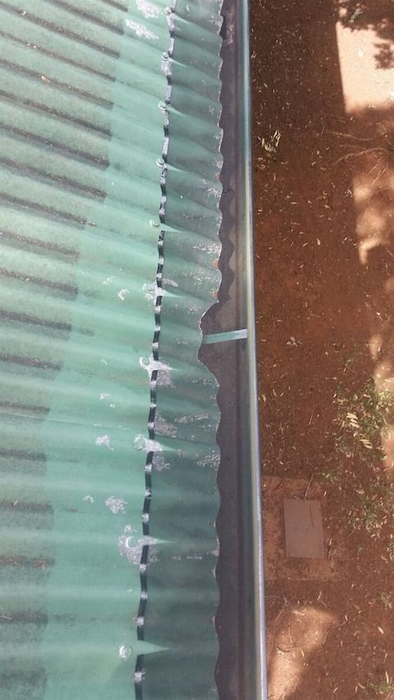 A Close Up of a Gutter on a Roof With Water Coming Out of It — AD House Wash & Gutter Cover in East Toowoomba, QLD