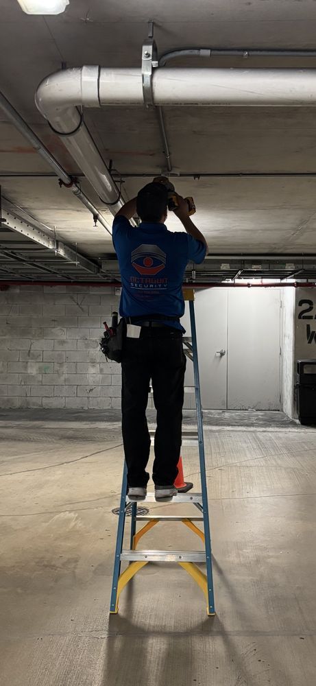 A man is standing on a ladder in a parking garage.
