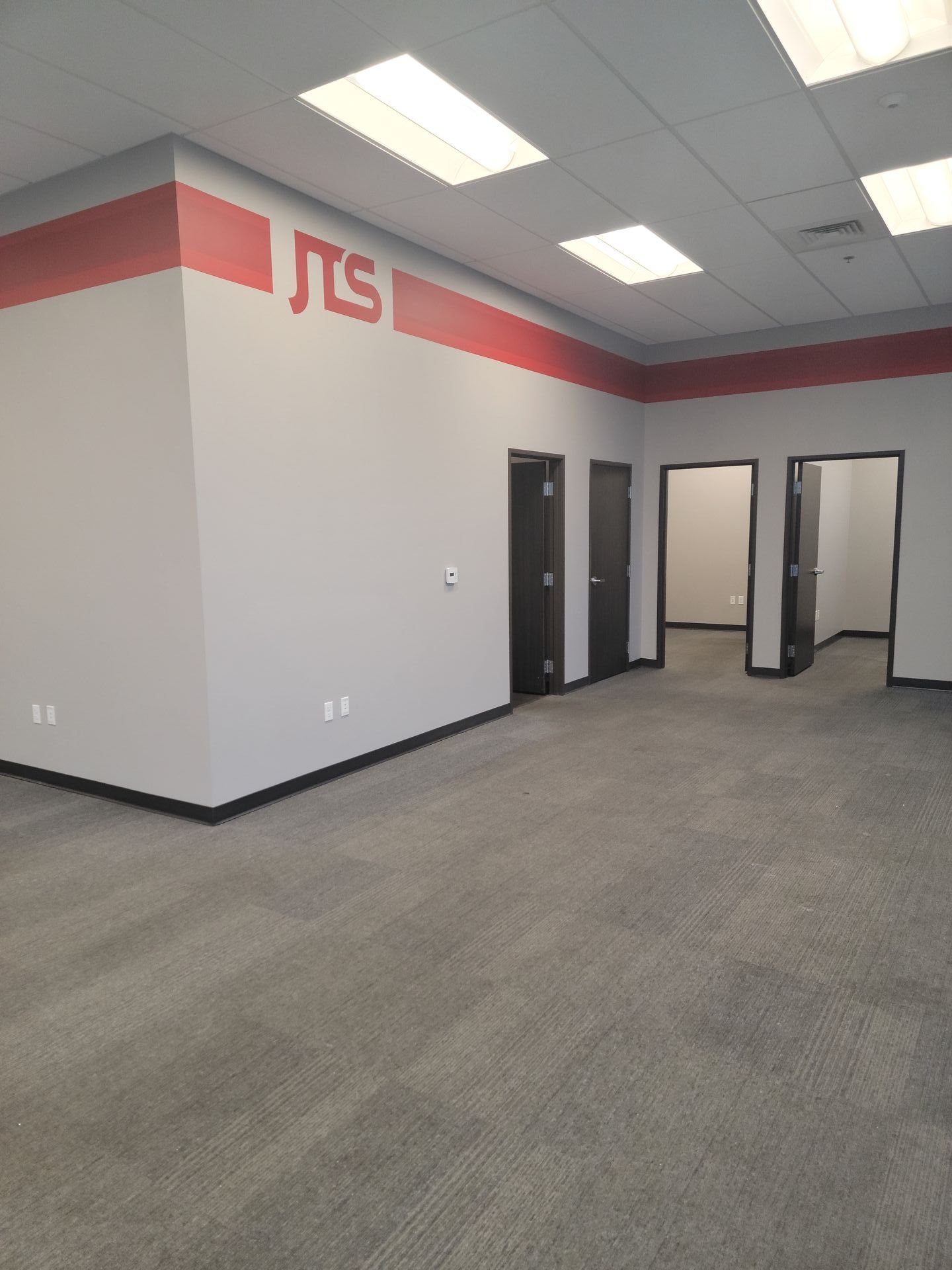 An empty room with a red stripe on the wall that says jts