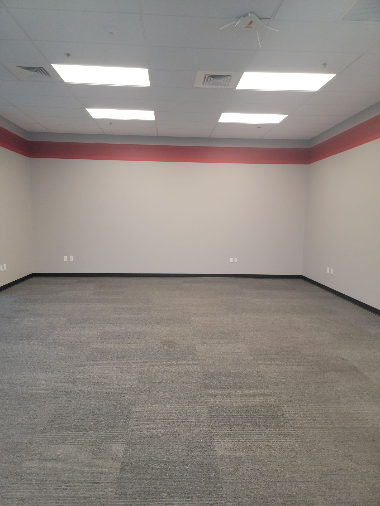 An empty room with a carpeted floor and white walls.