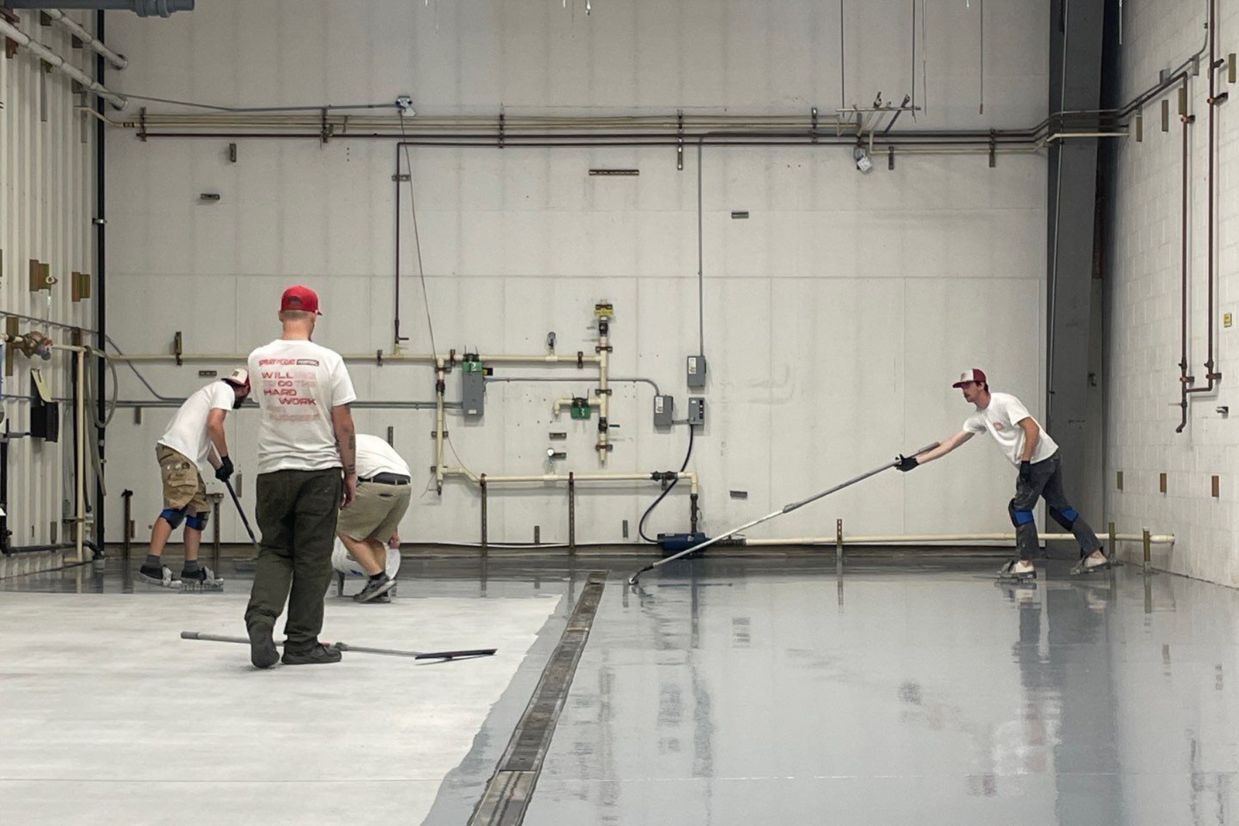 A group of men are working on a concrete floor in a large room.