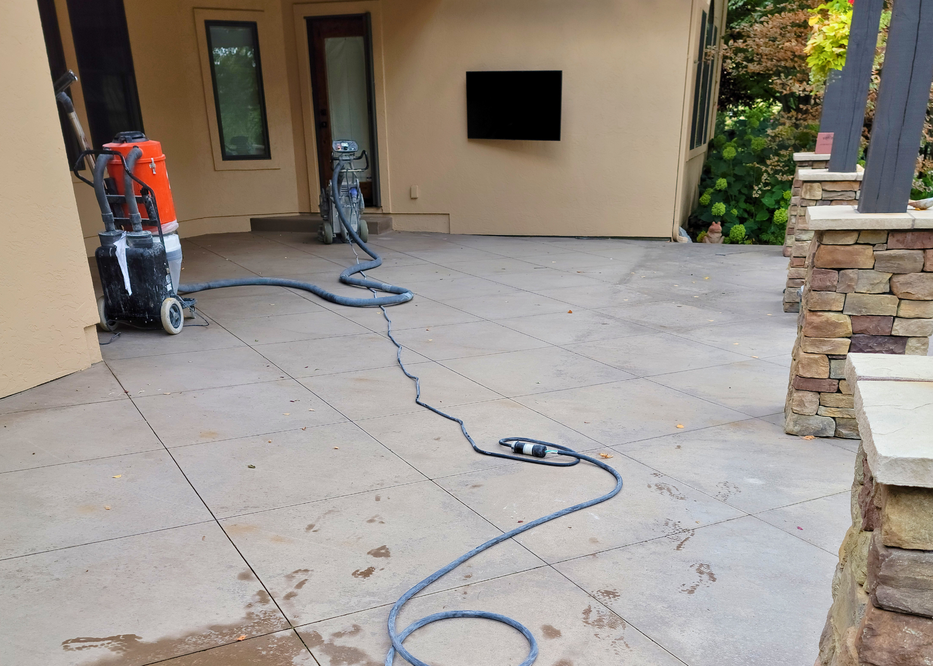 A vacuum cleaner is sitting on a concrete patio in front of a house.