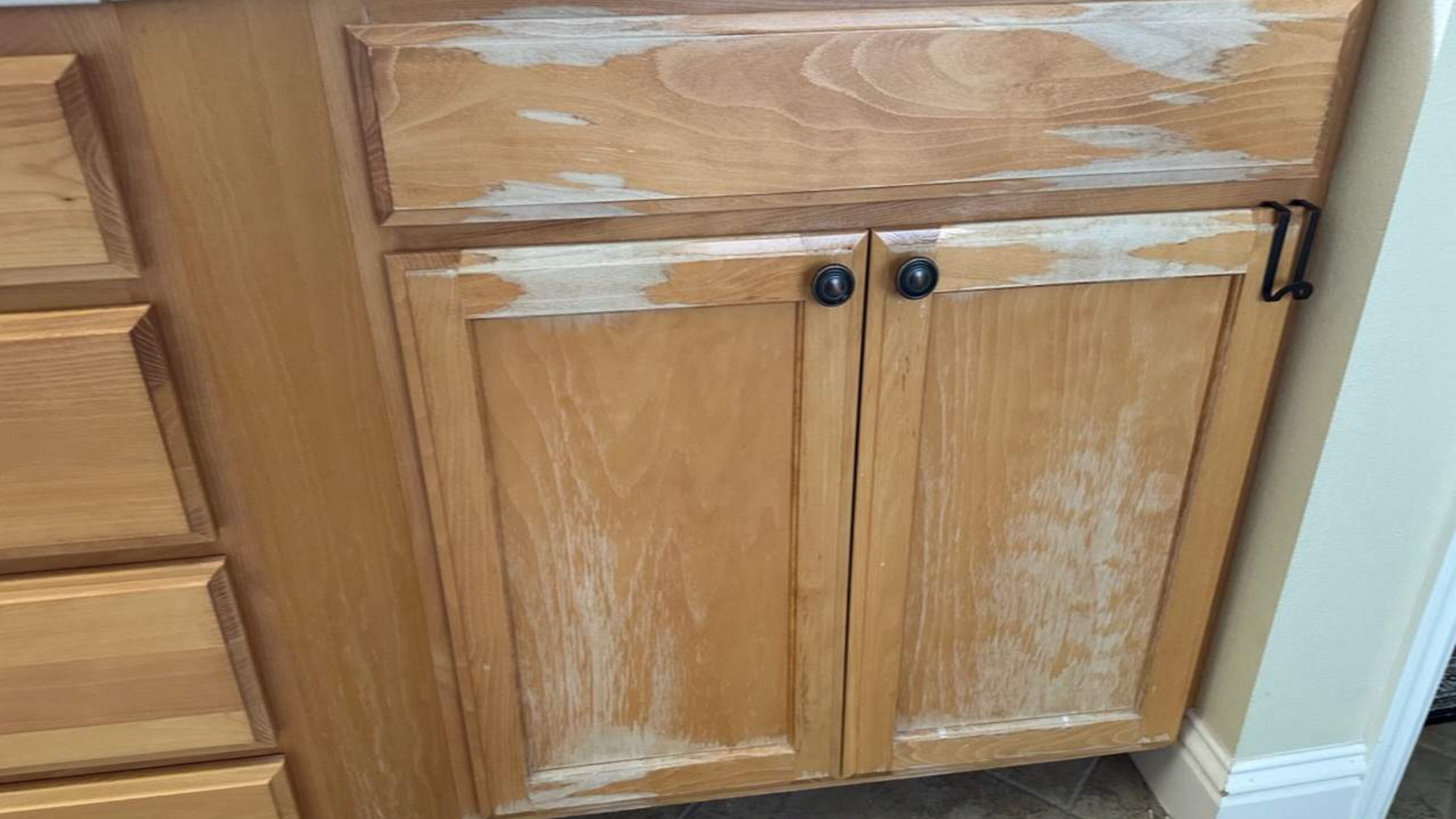 Water-damaged wood cabinet showing peeling finish and bubbling from moisture exposure