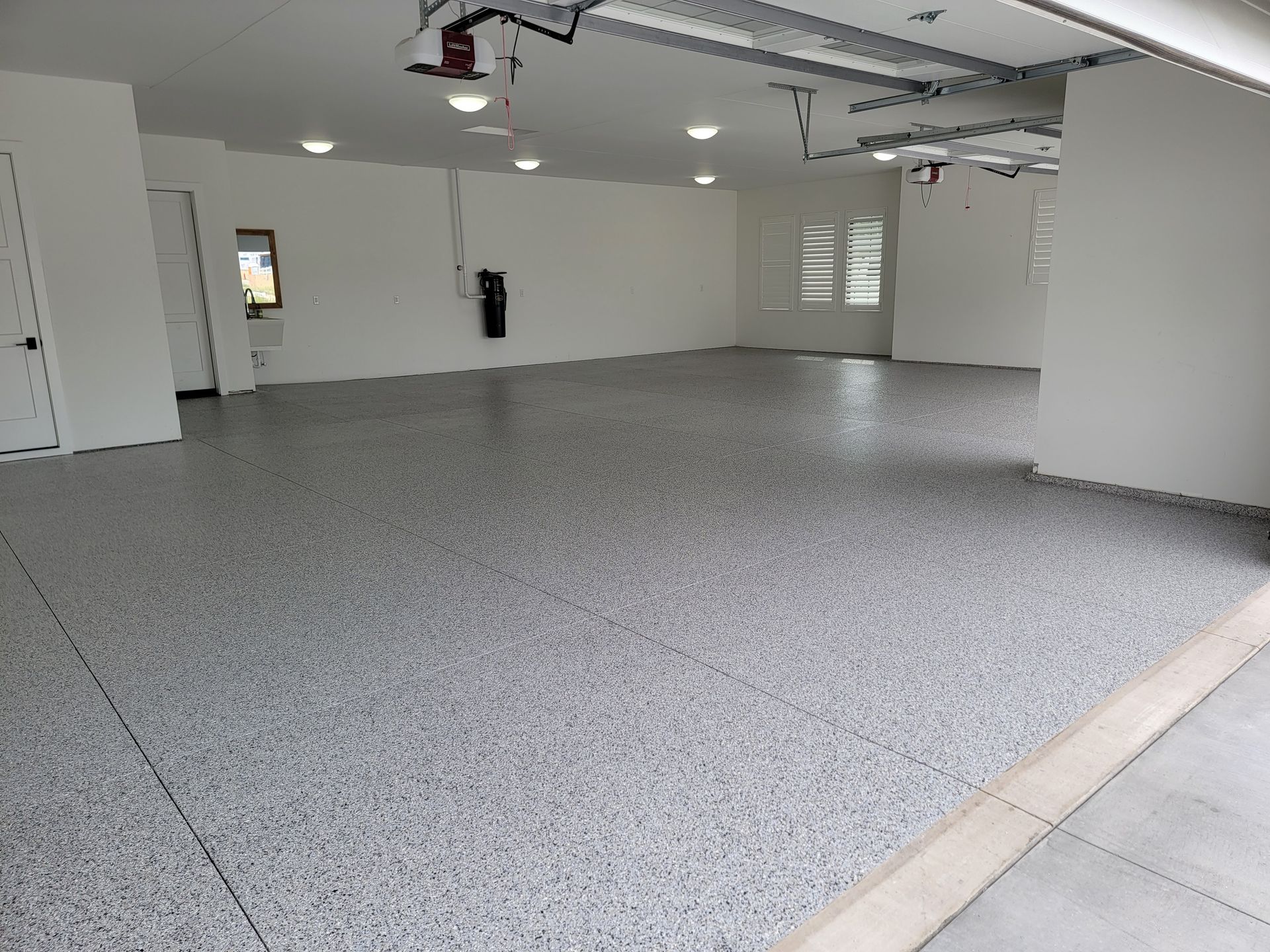 A large empty garage with a gray floor and white walls.