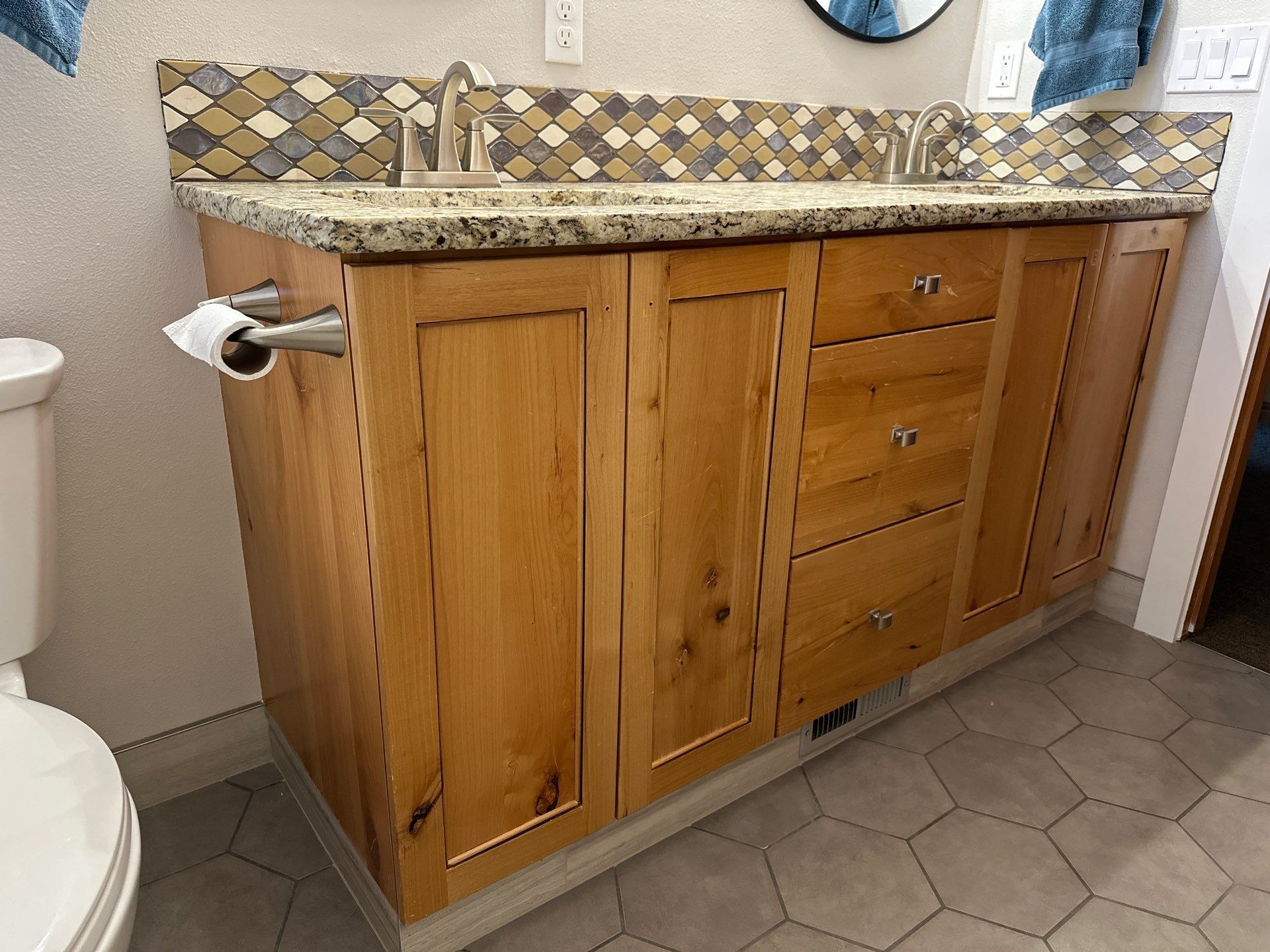 A bathroom with a sink , toilet and wooden cabinets.