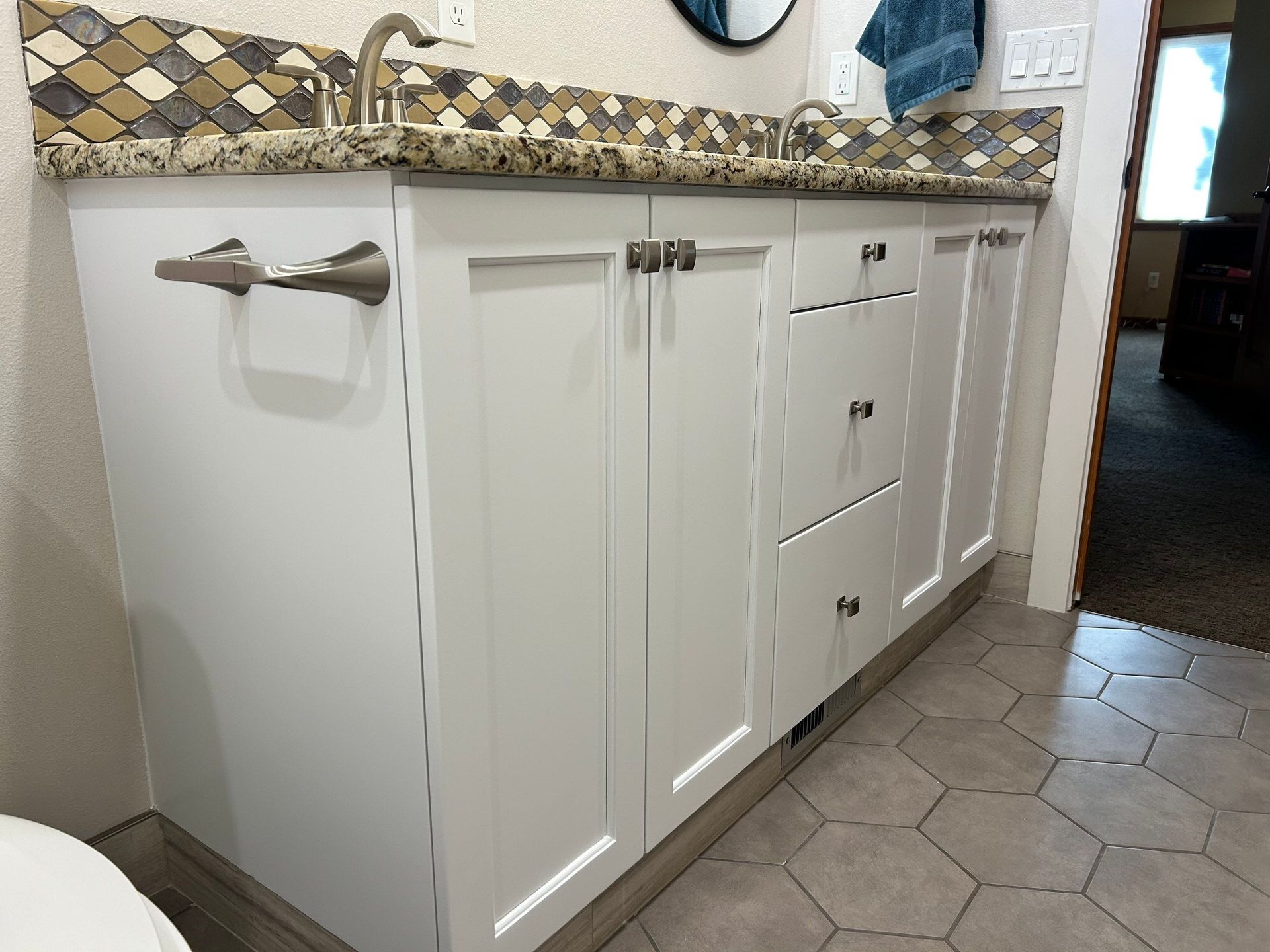 A bathroom with a sink , cabinets , and a toilet.