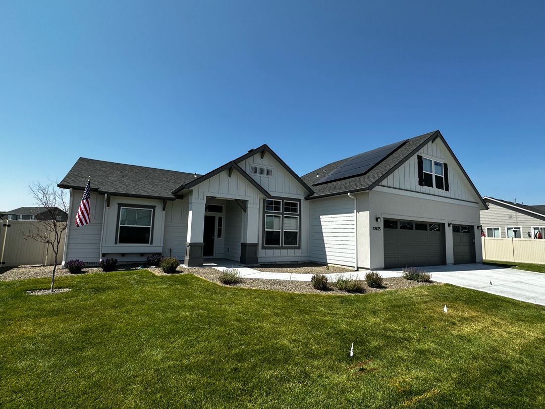 A large white house with a gray roof is sitting on top of a lush green lawn.