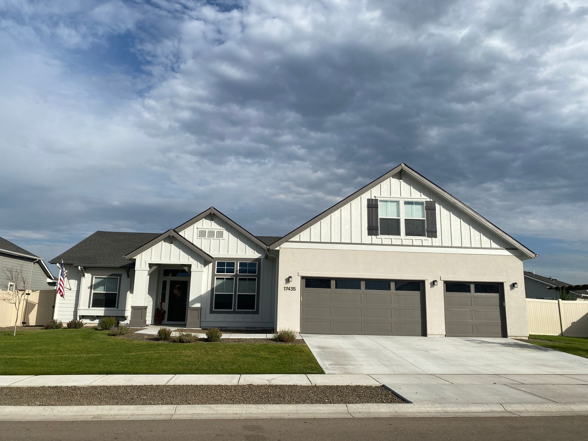 A large white house with a gray garage door is for sale.