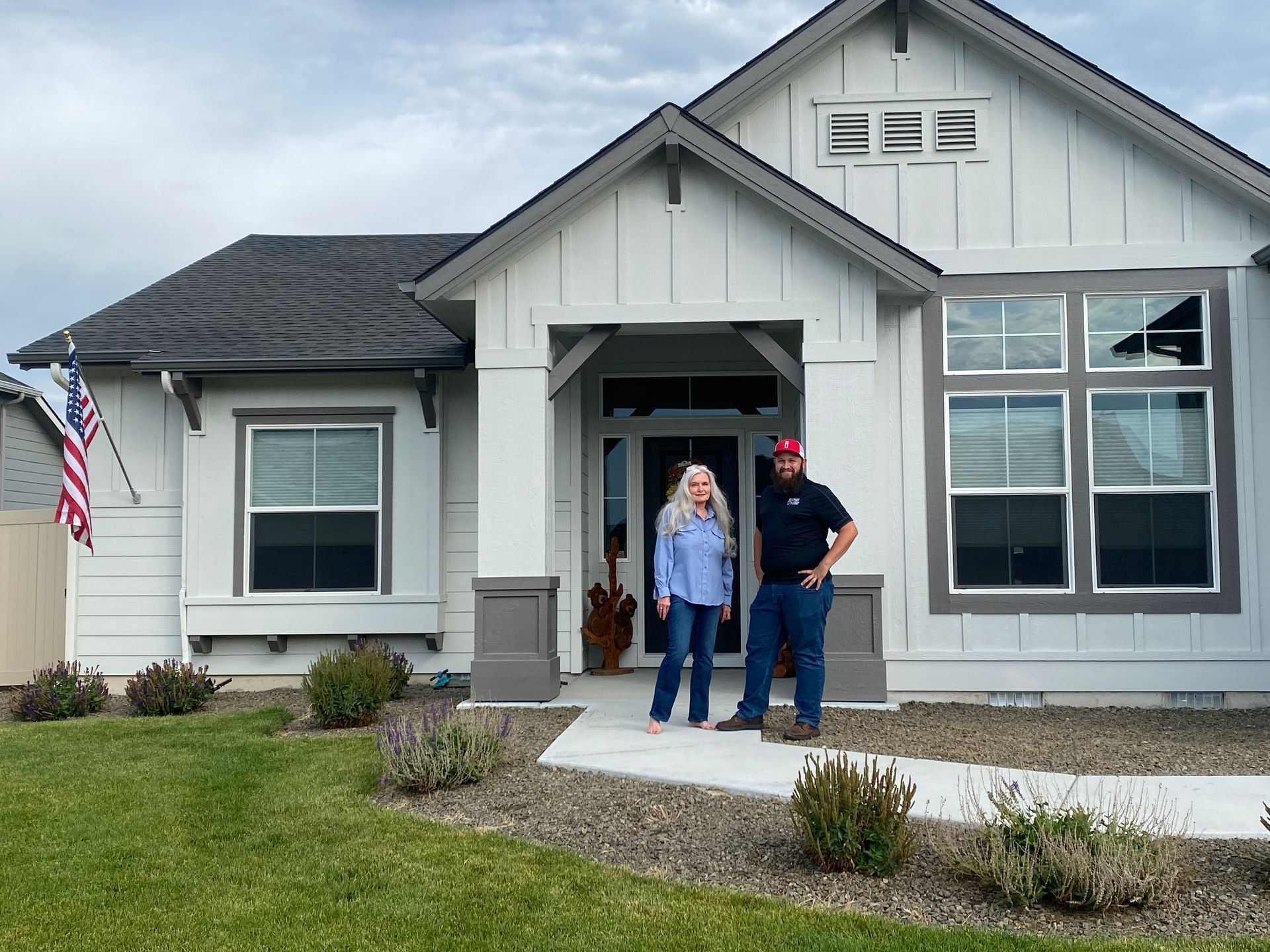 A man and a woman are standing in front of a white house.