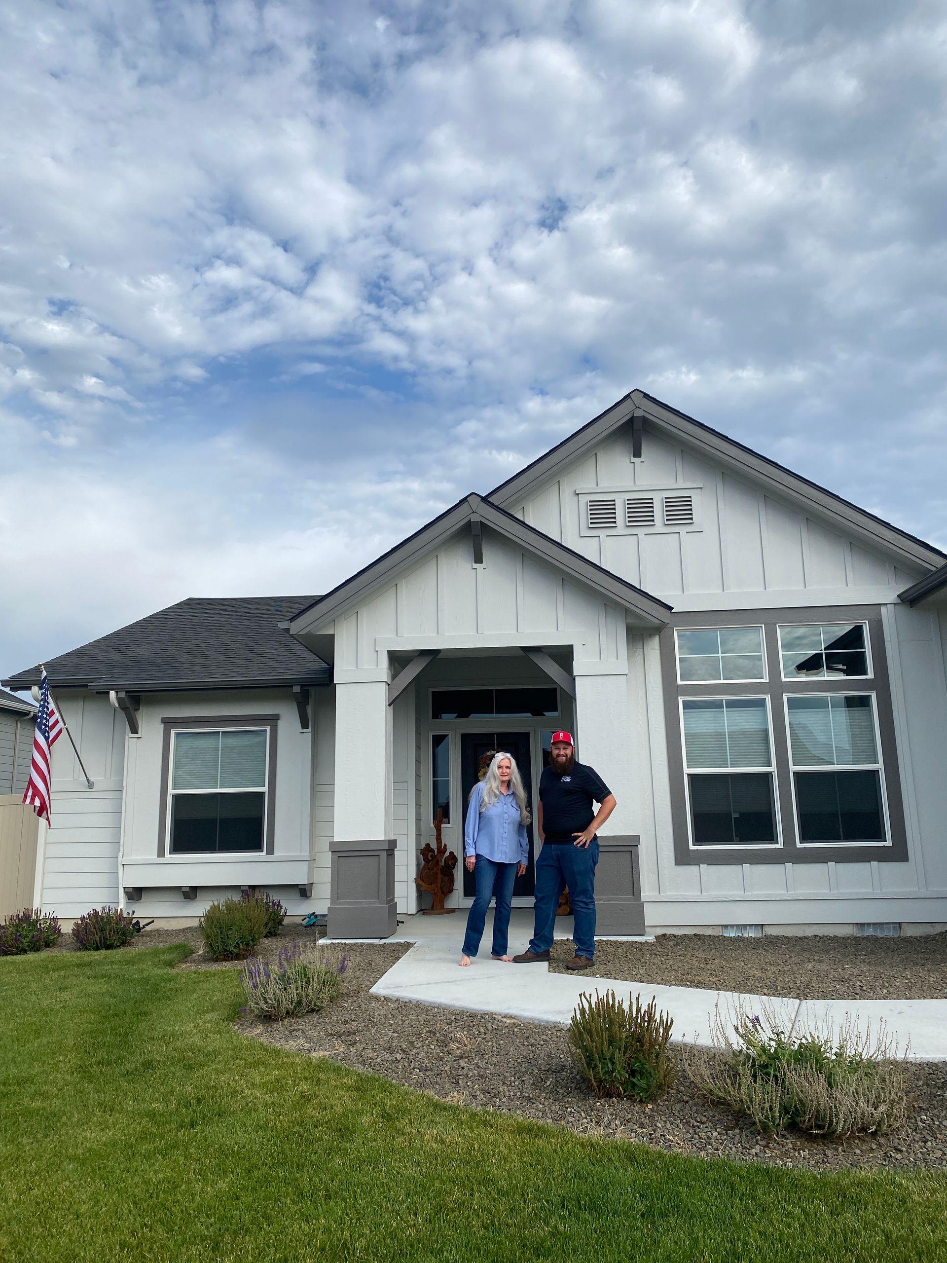 Two people are standing in front of a white house.