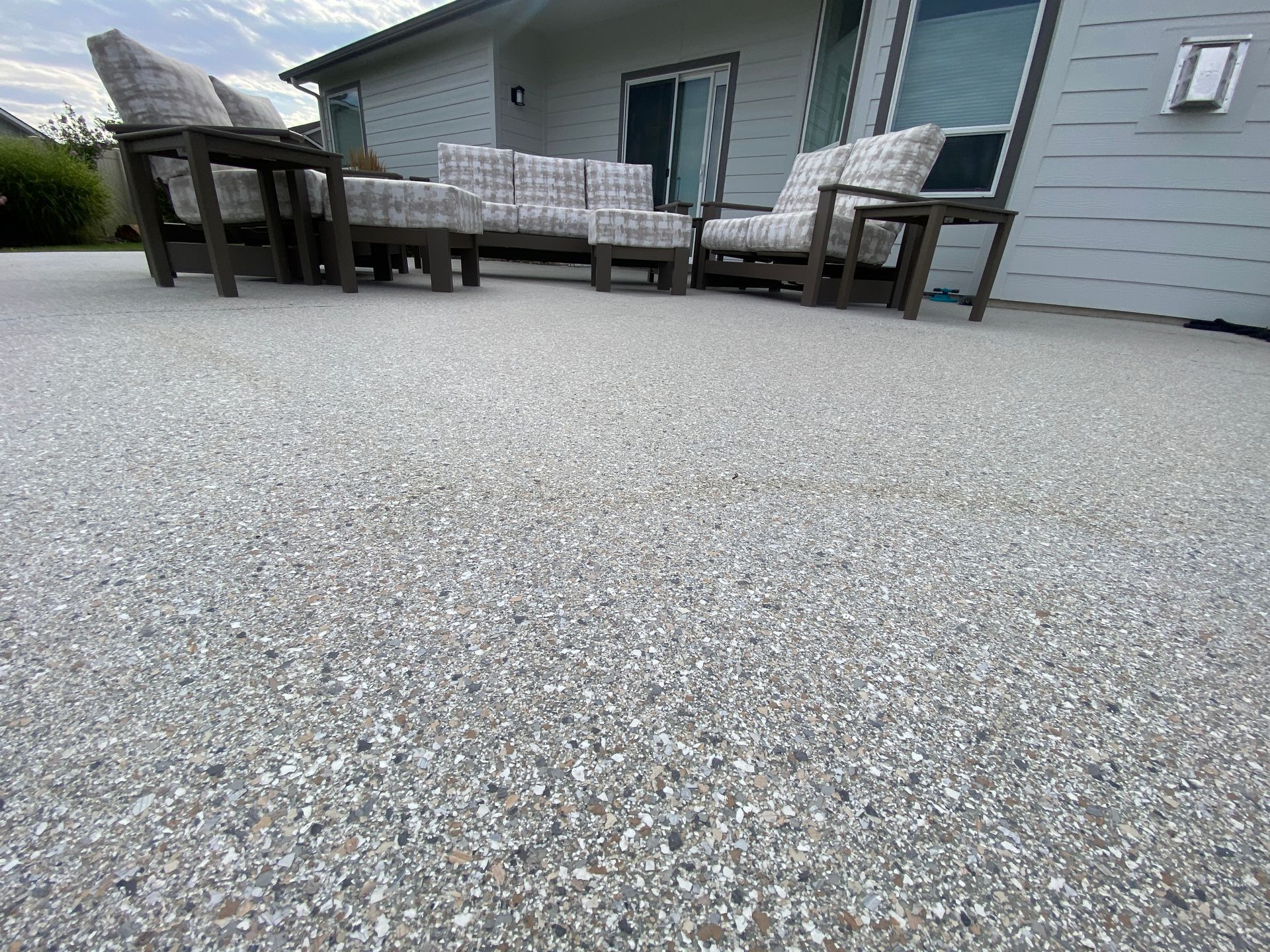 A patio with a couch and chairs on it in front of a house.