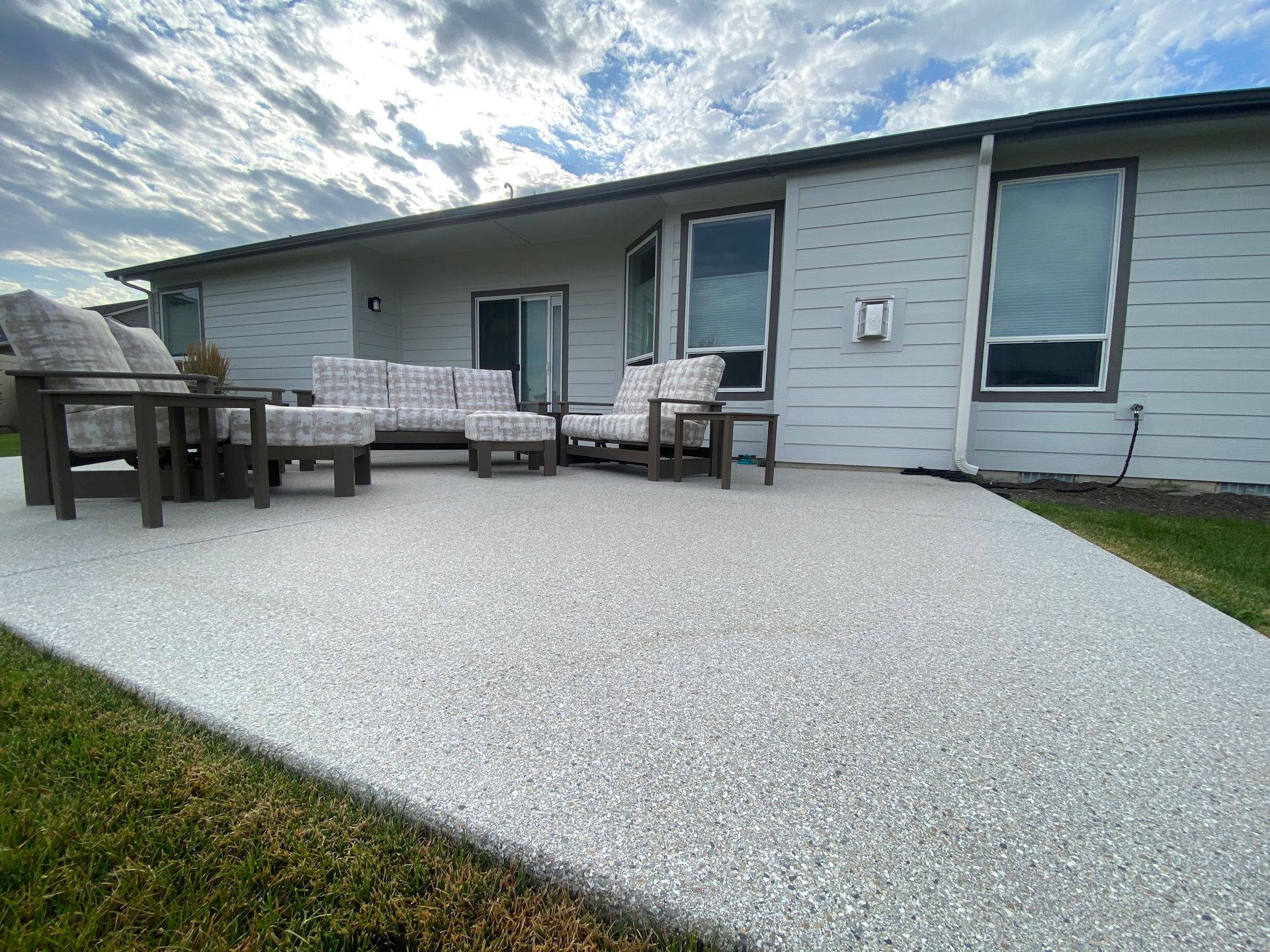 A patio with a couch and chairs in front of a house.