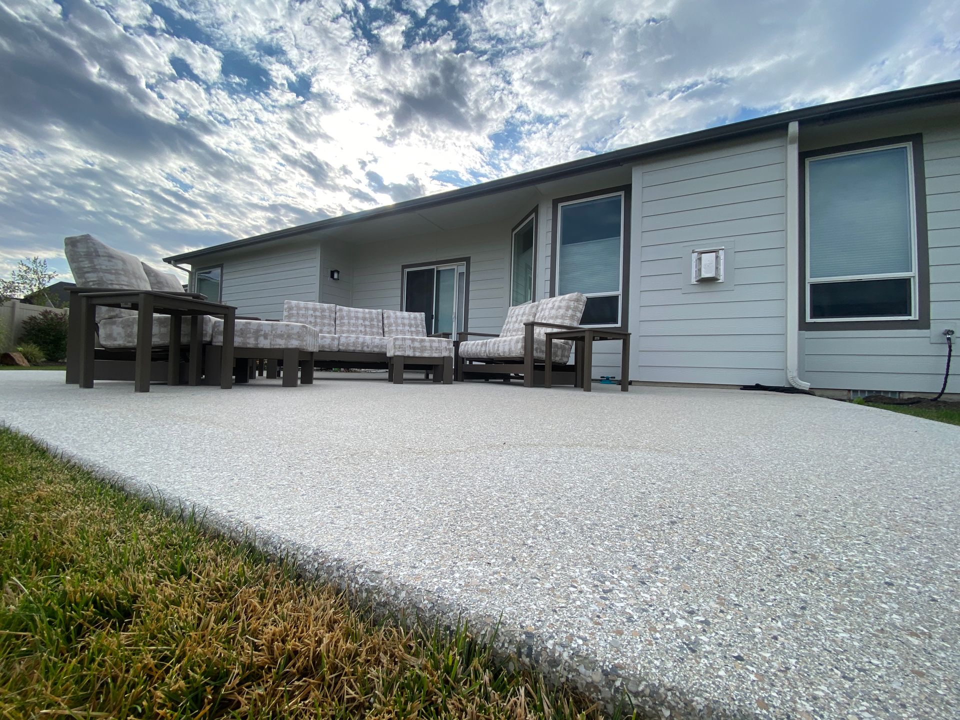 A patio with a couch and chairs in front of a house.