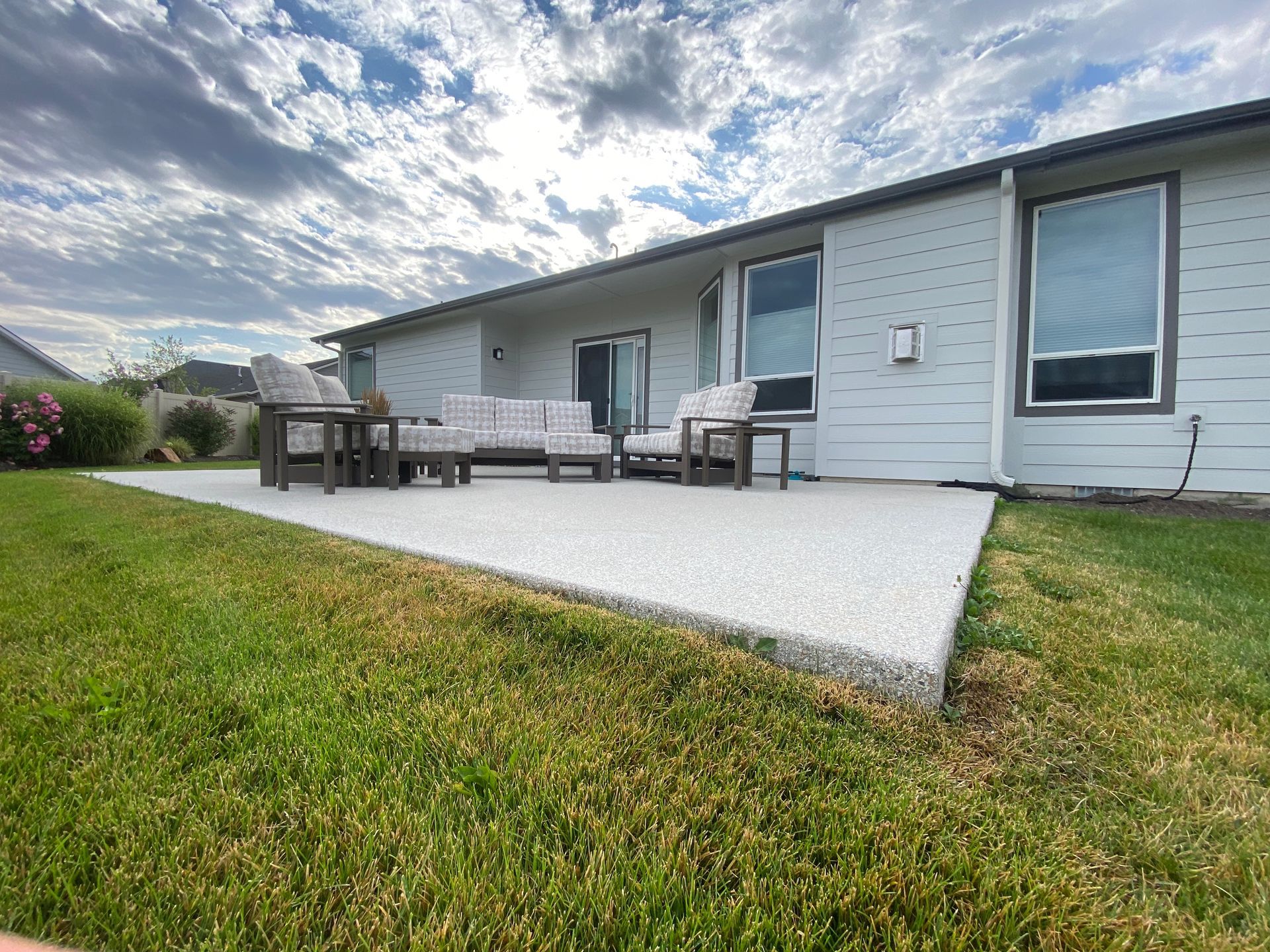 A patio with a couch and chairs in front of a house.
