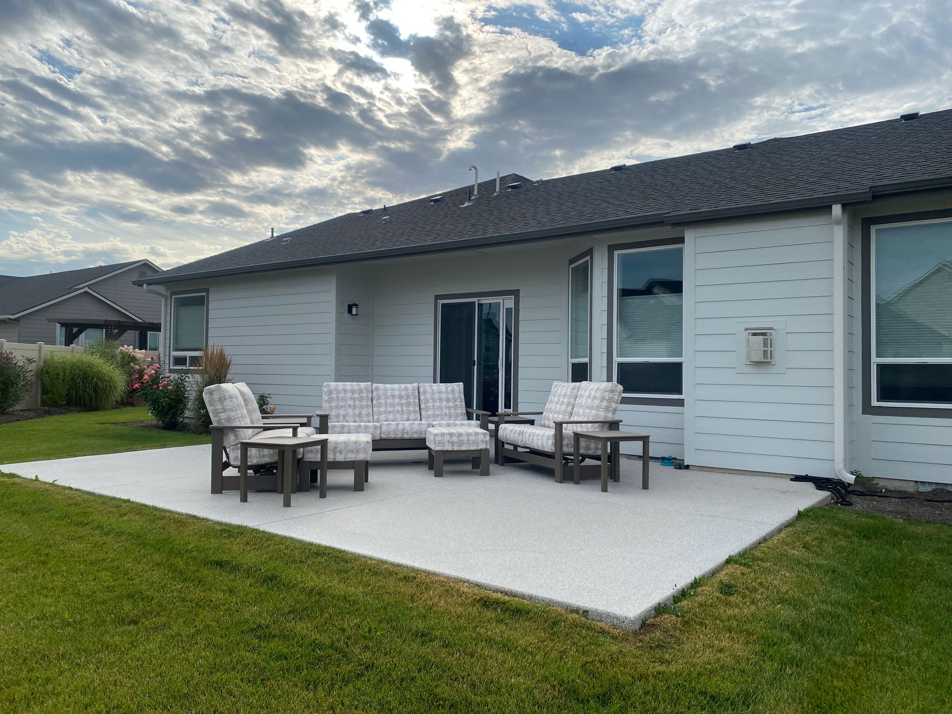 A patio with a couch and chairs in front of a house.