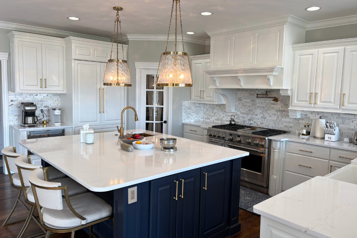 Modern kitchen with white cabinets, navy island, and brass fixtures.