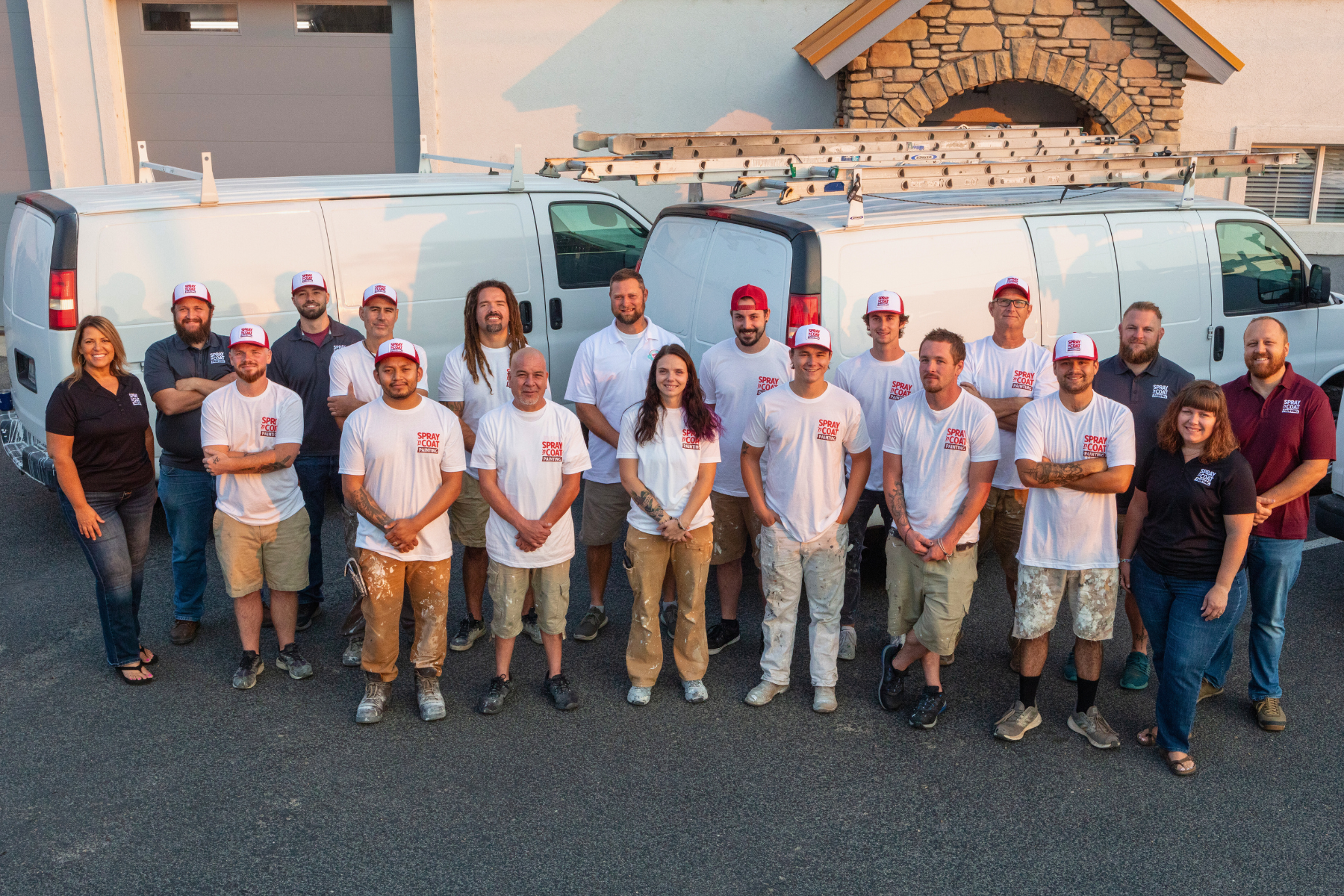 A group of people are posing for a picture in front of their vans.