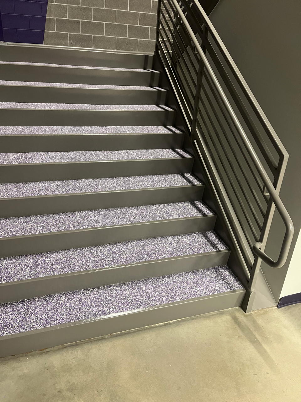 A set of stairs with a metal railing and purple steps.
