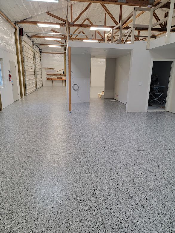 A large empty room with a gray floor and a white wall.