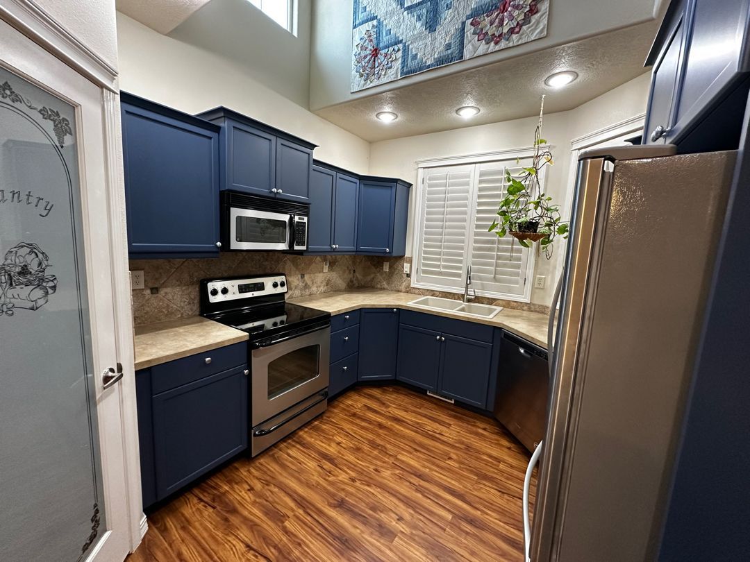 A kitchen with blue cabinets and stainless steel appliances