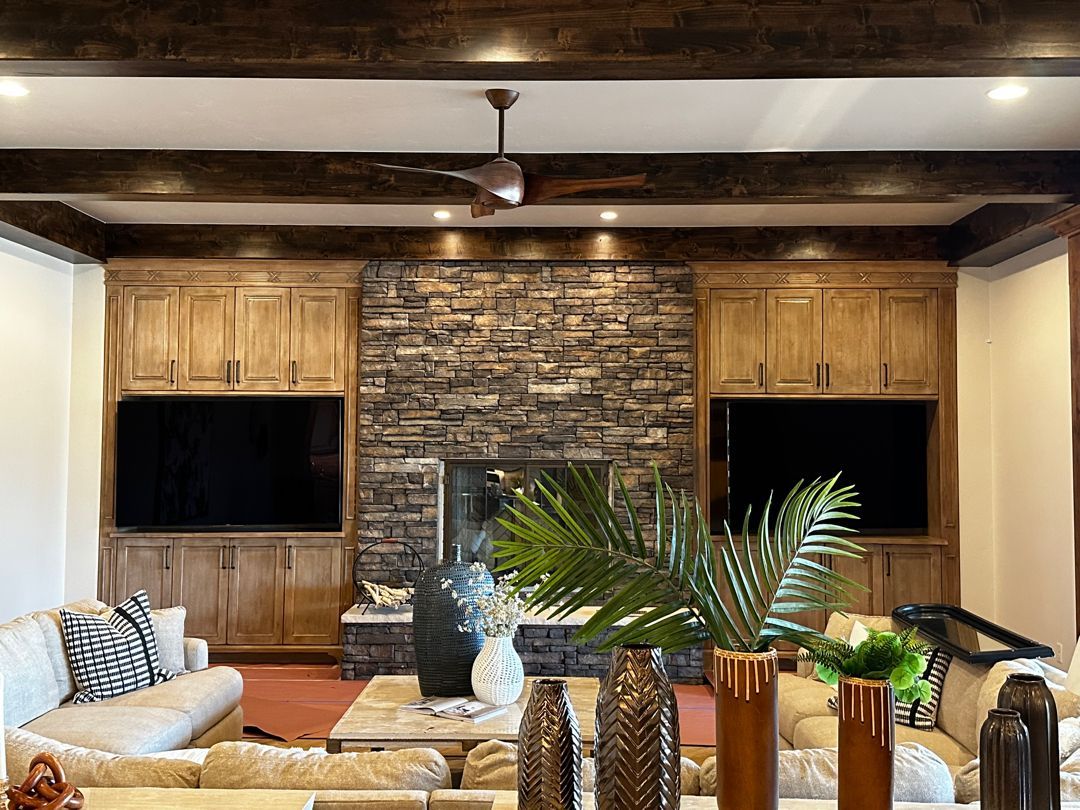 A living room with a stone fireplace and a ceiling fan.