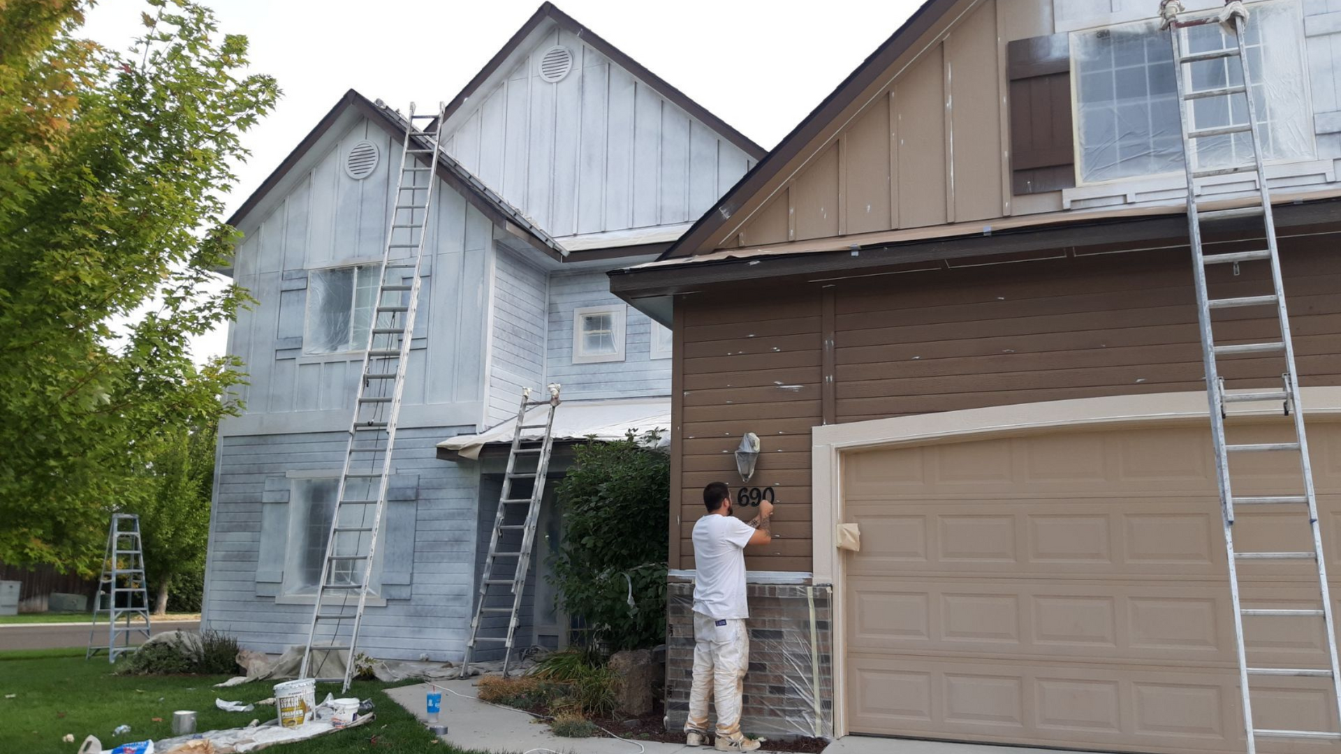A man is standing in front of a house that is being painted.