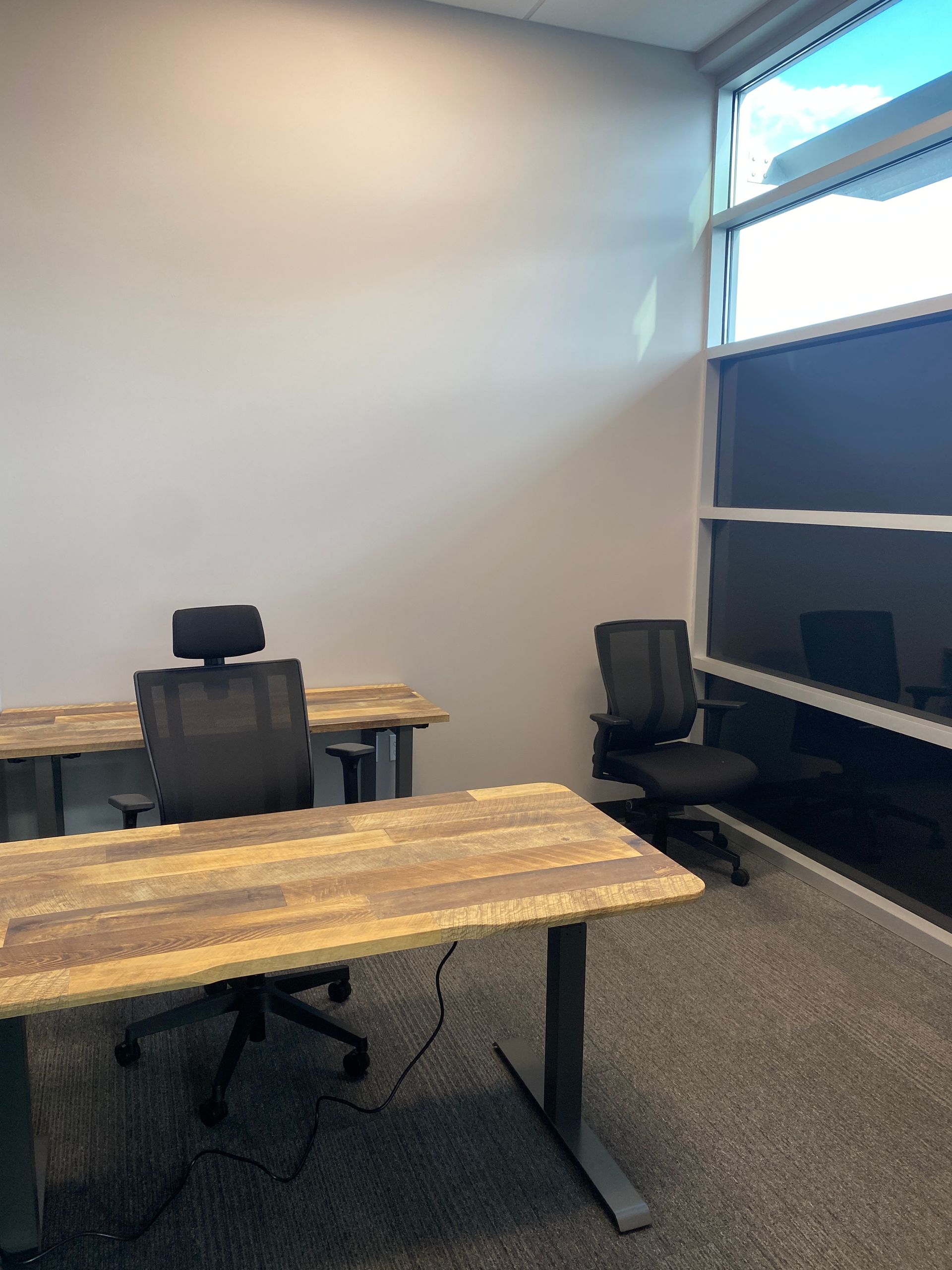 A small office with two desks and two chairs.