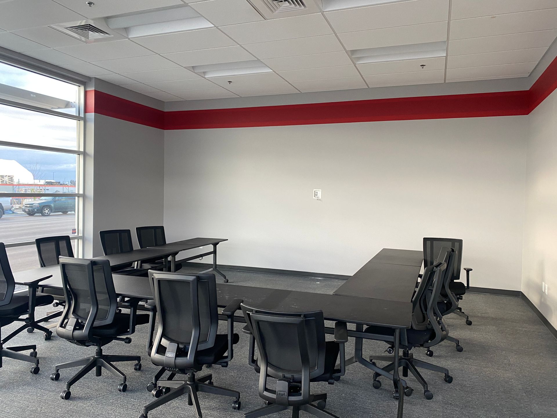A conference room with tables and chairs and a large window.