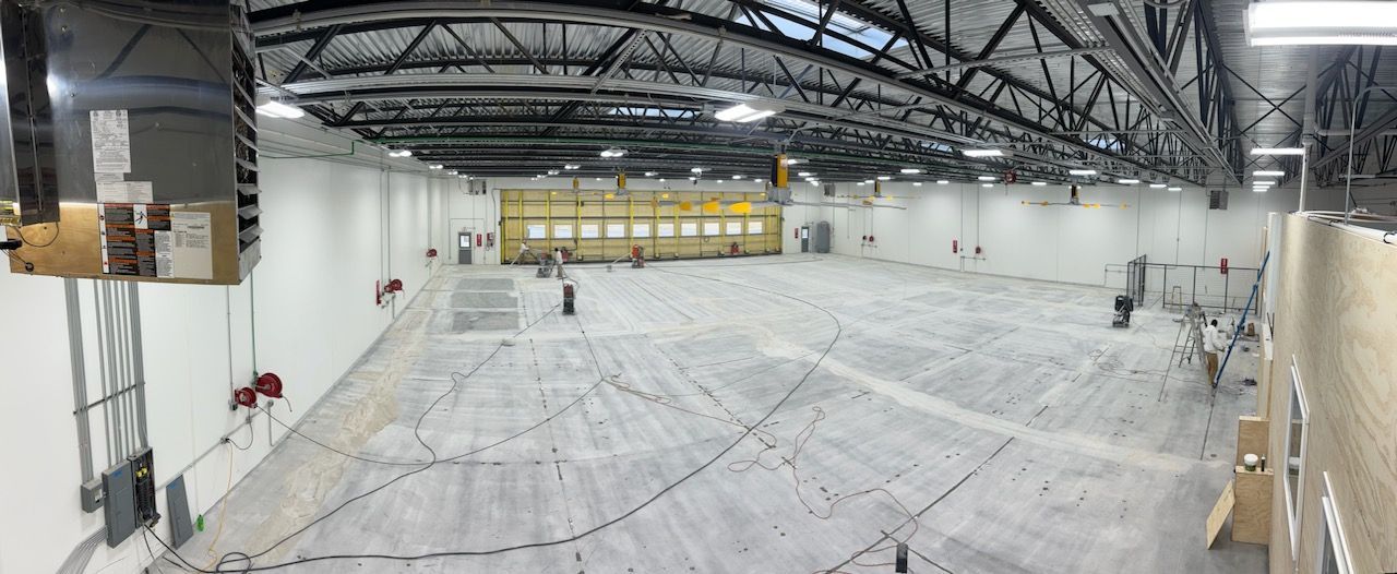 A large empty warehouse with a concrete floor and a yellow door.