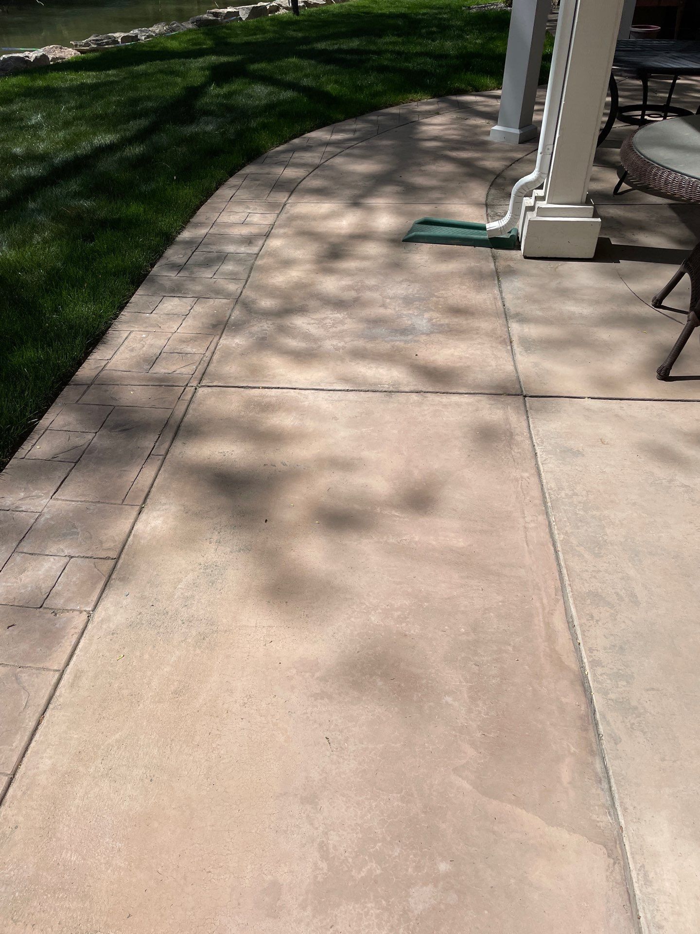 A patio with a shadow of a tree on the sidewalk.