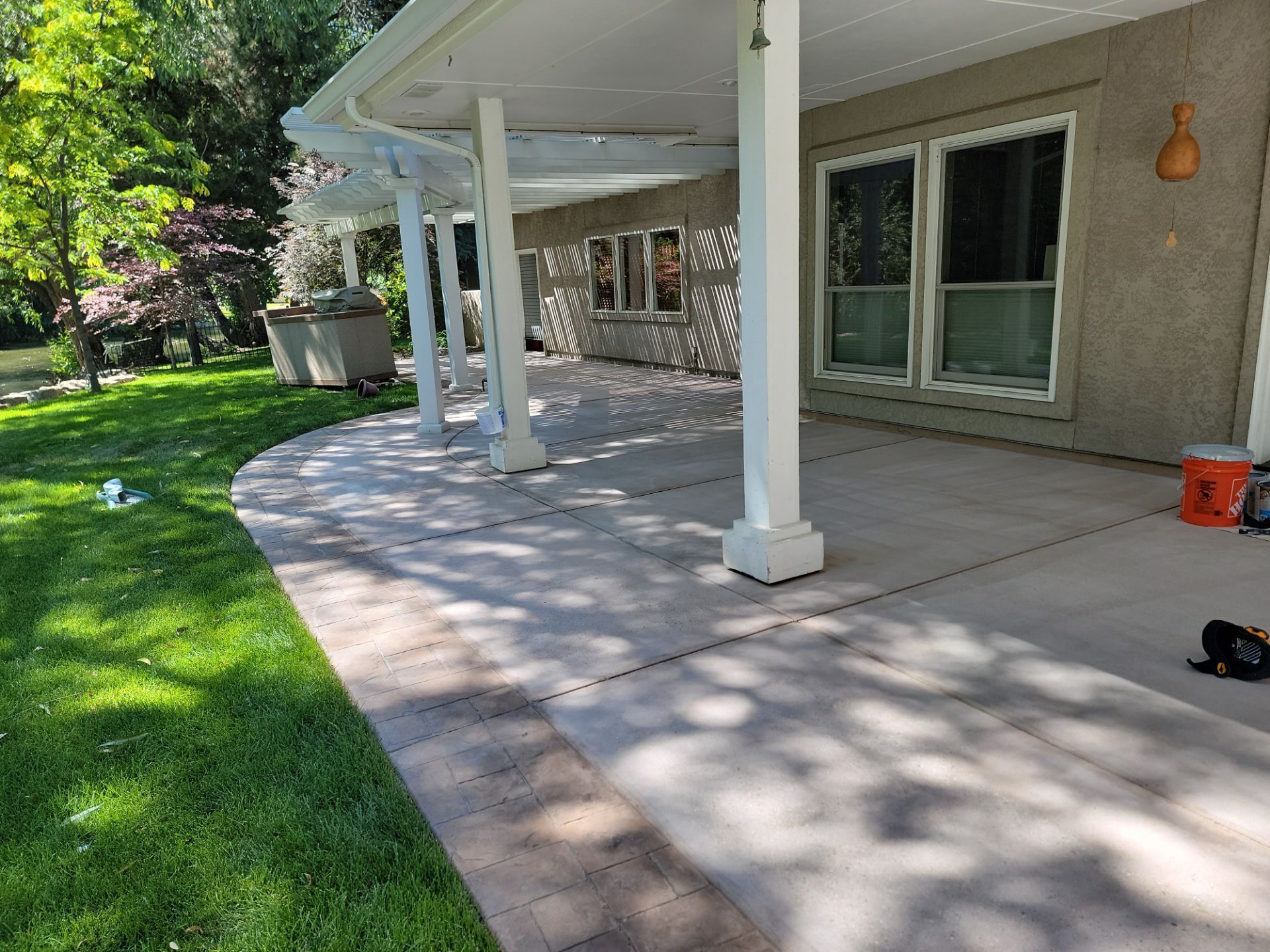 A house with a covered patio and a lawn in front of it.