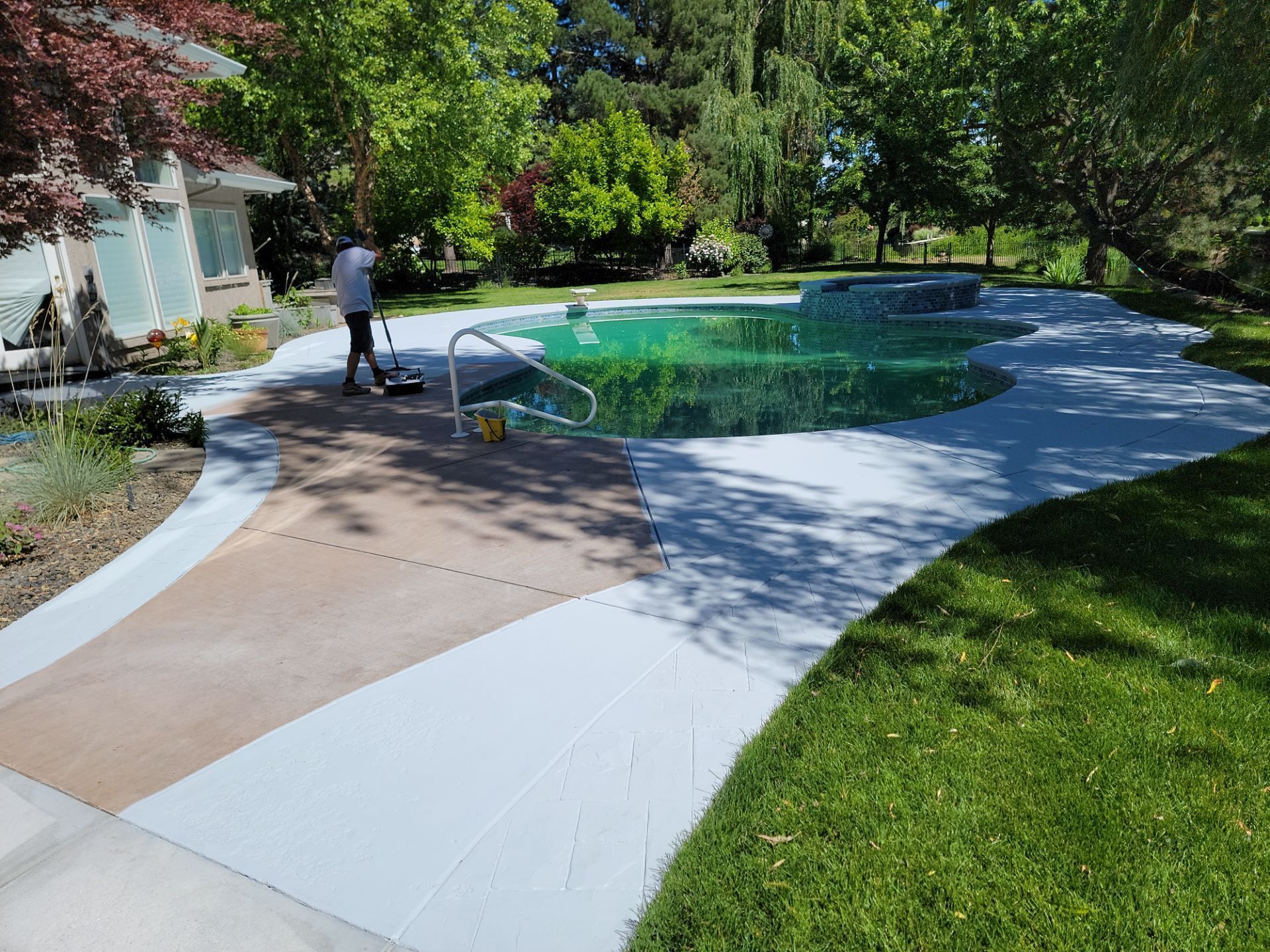 A man is standing next to a swimming pool in a backyard.