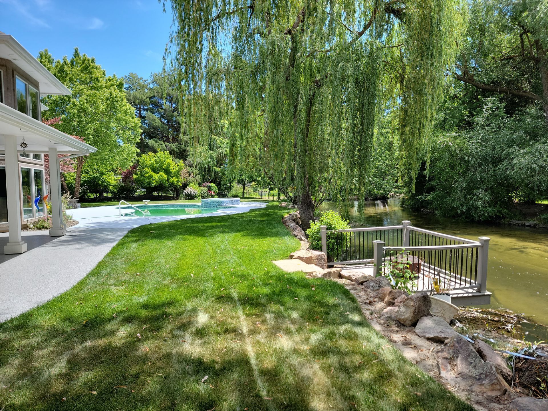 A large house with a lush green lawn and a pond in the backyard.