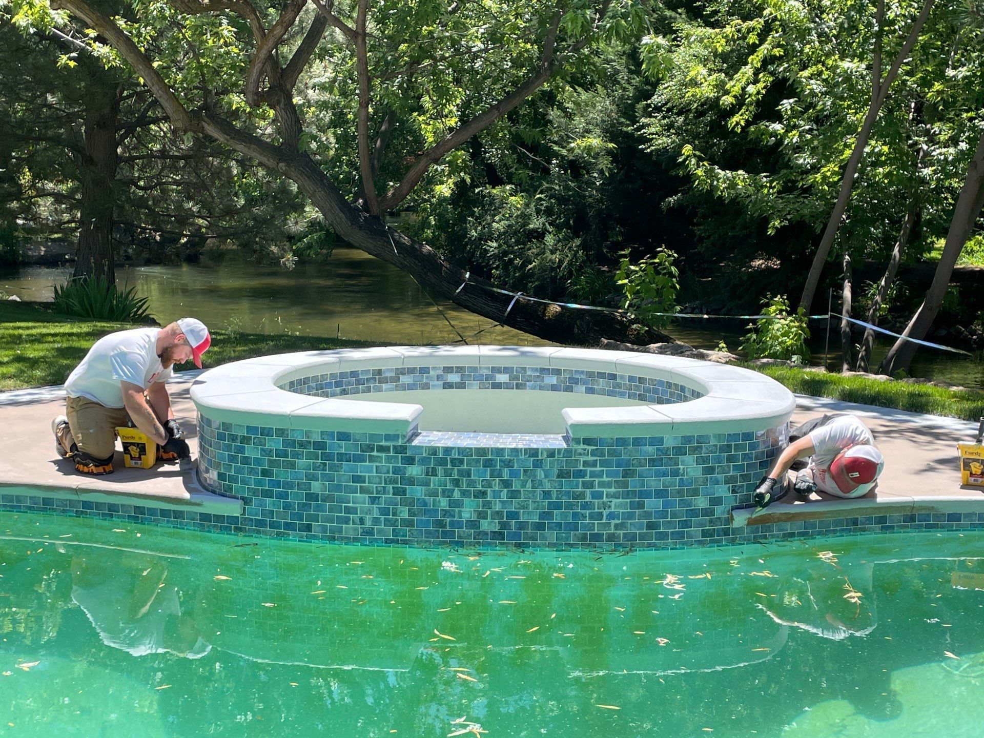 Two men are working on a hot tub in a swimming pool.