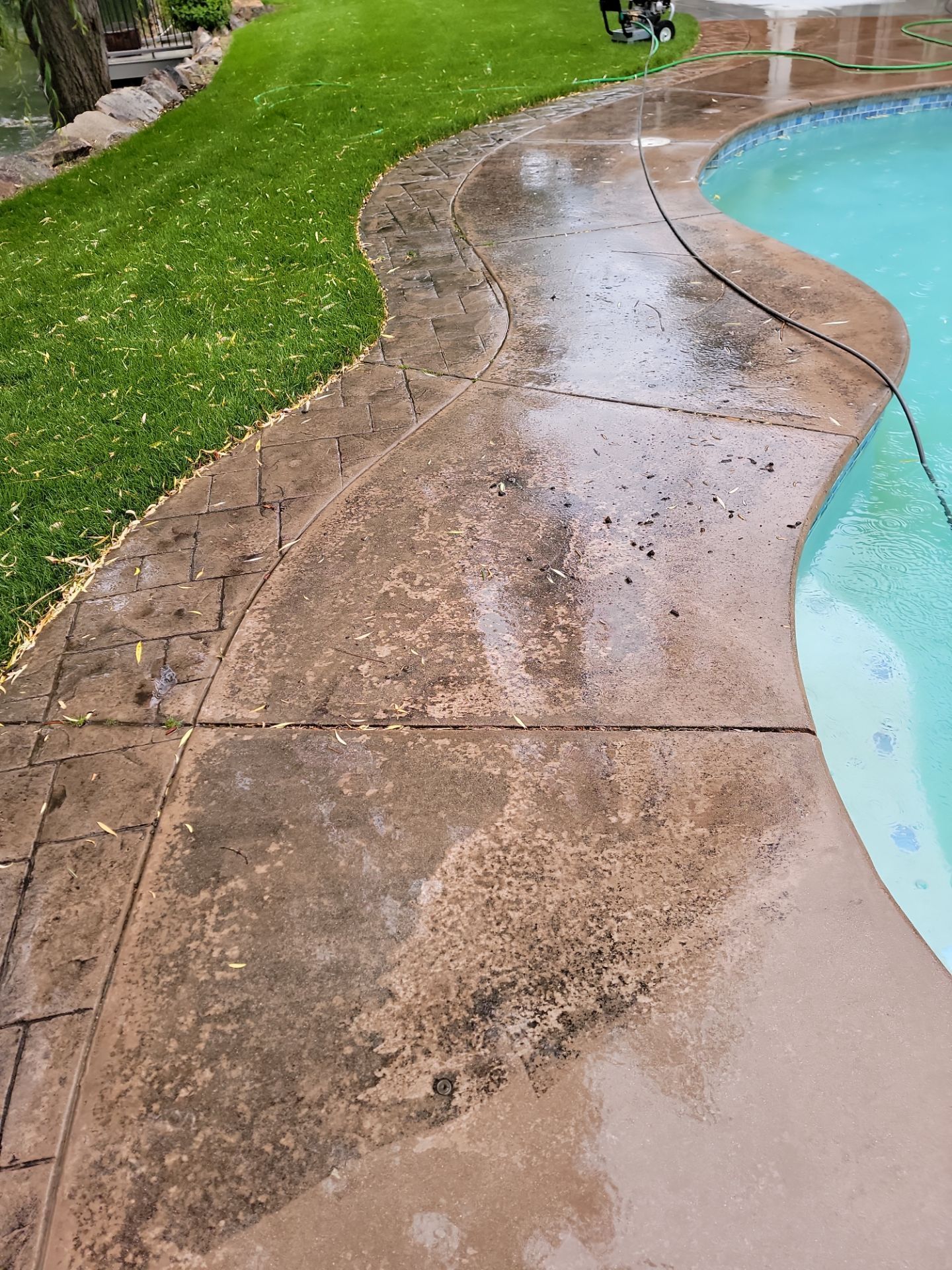 A dirty concrete walkway next to a swimming pool.