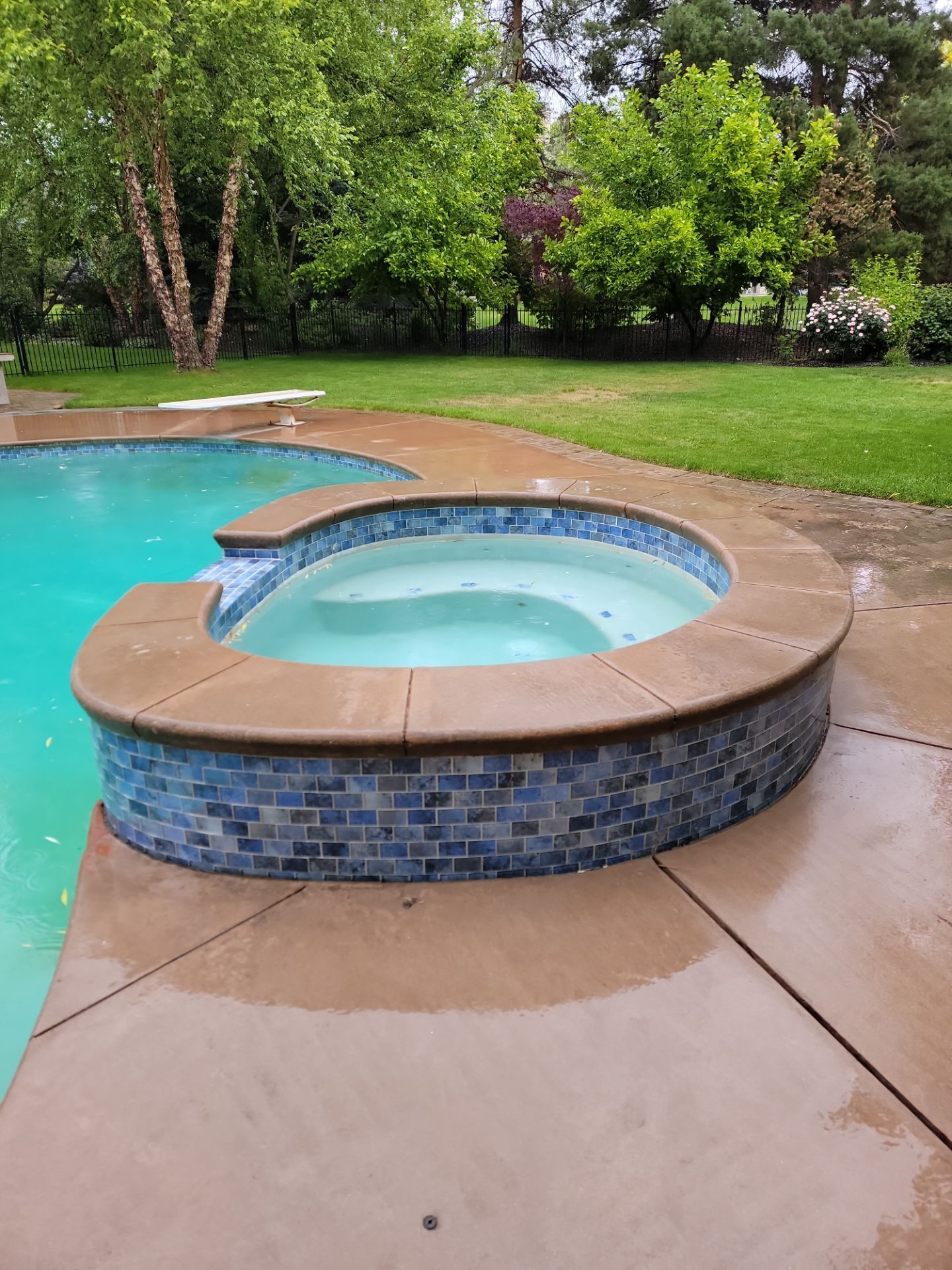 A hot tub is sitting next to a swimming pool.