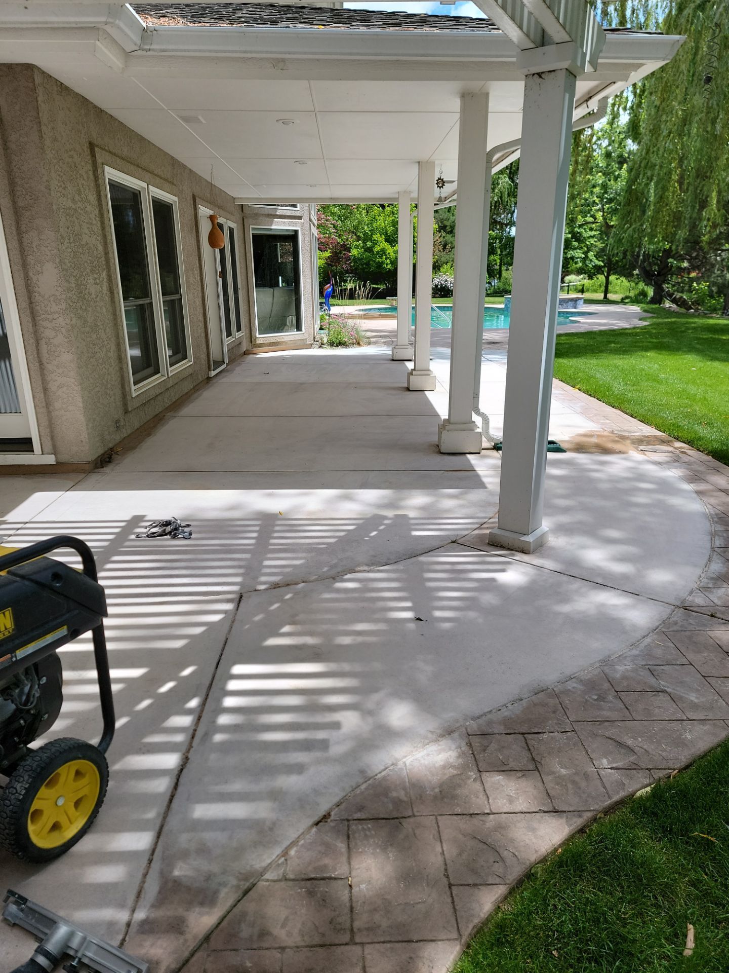 A generator is sitting on the sidewalk in front of a house.