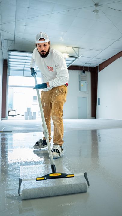 A man is painting a floor with a roller.