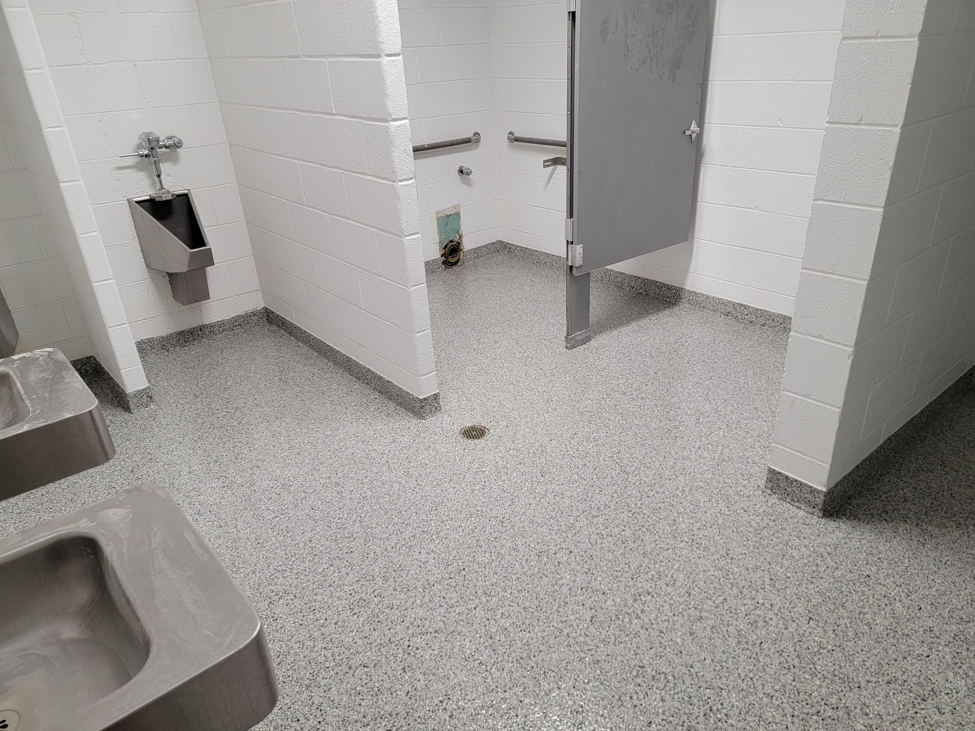 A bathroom with a urinal , sink , and toilet.
