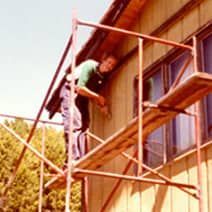 A man is standing on a scaffolding next to a building.