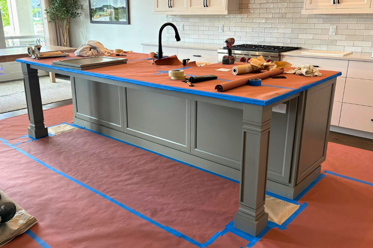 Kitchen covered with paper and tools during cabinet painting.