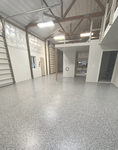 A large empty garage with a concrete floor and stairs.
