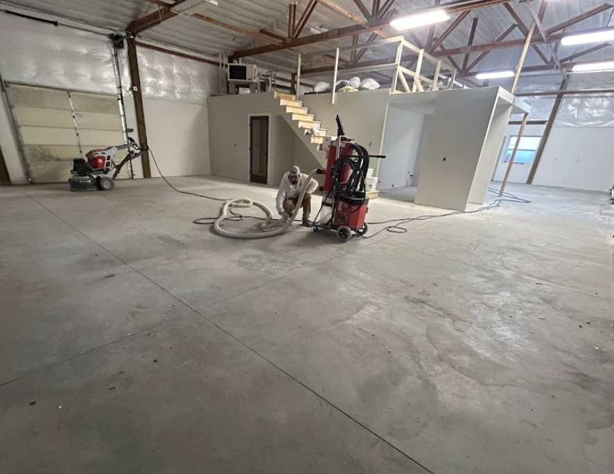 A man is working on a concrete floor in a warehouse.