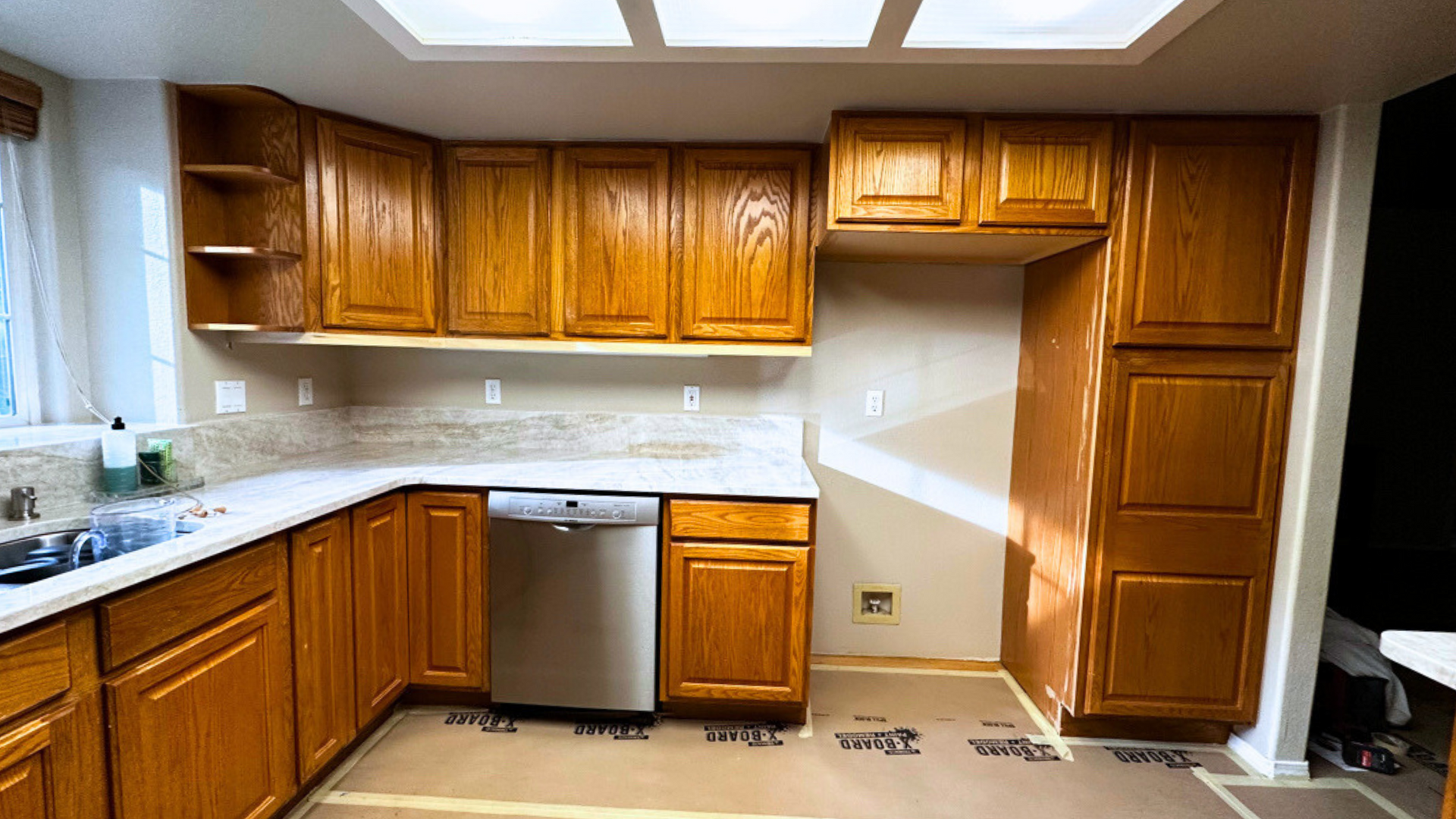 A kitchen with wooden cabinets and a stainless steel dishwasher.