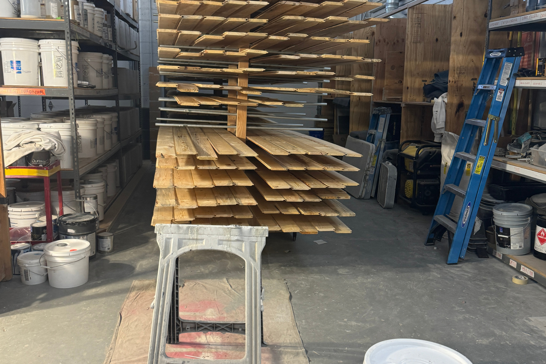 A stack of wood is sitting on top of a metal table in a warehouse.