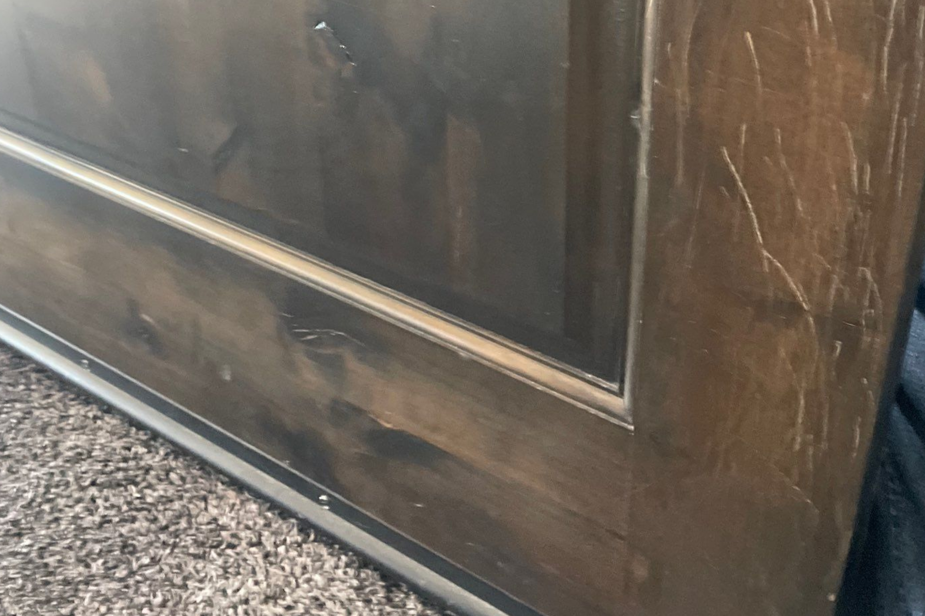 A wooden cabinet is sitting on top of a carpeted floor.