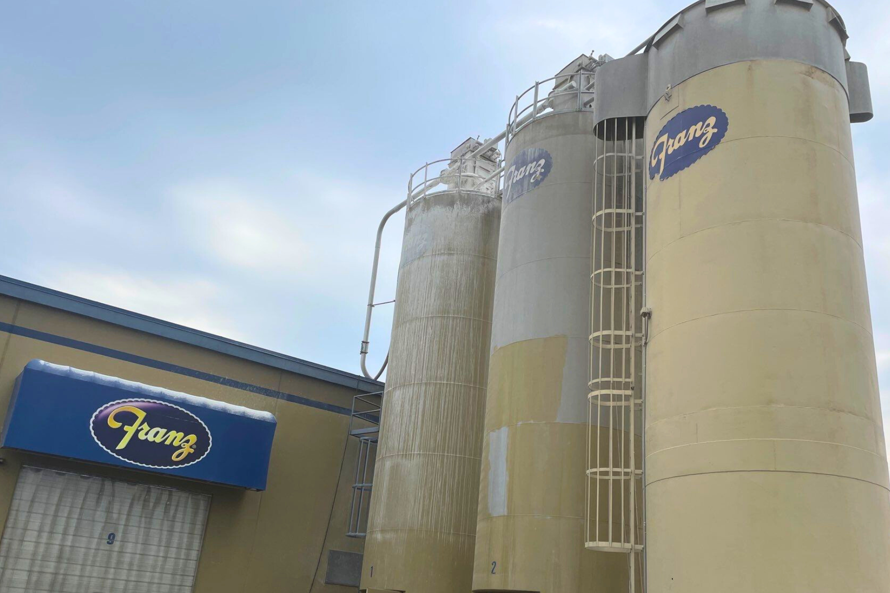 A large building with a lot of silos and a ladder on the side of it.